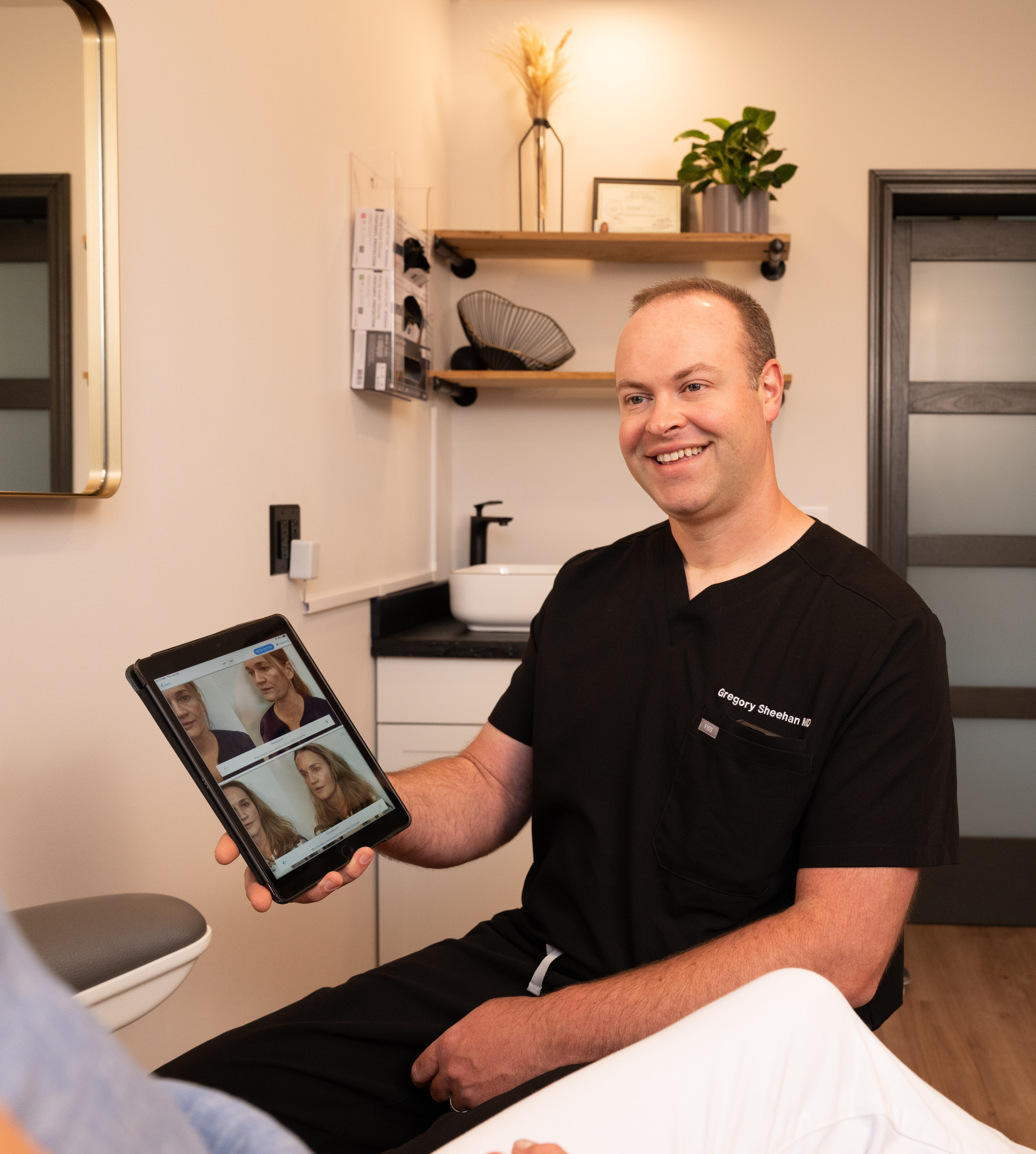 Dr. Greg Sheehan showcasing patient before and after photos during a consultation